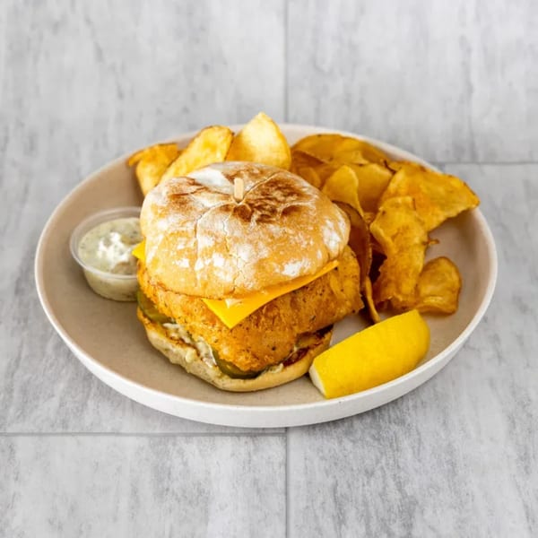 Uncle Mac's Kitchen fish sandwich with cheese, pickles, tartar sauce, and a side of chips.